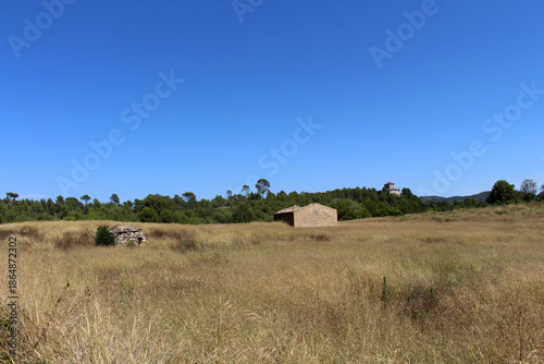 Empty field with rural houses along the route from Montserrat to Manresa in Catalonia, Spain, taken in July 2024.