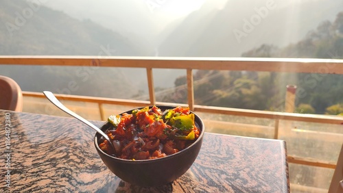 Mushrooms Manchurian dry in black bowl with beautiful view of mountains. Mushroom Manchurian - is indo chinese cuisine dish with deep fried mushrooms, bell peppers, sauce, capsicum and onion.