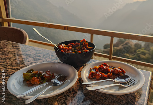 Mushrooms Manchurian dry in black bowl with beautiful view of mountains. Mushroom Manchurian - is indo chinese cuisine dish with deep fried mushrooms, bell peppers, sauce, capsicum and onion.