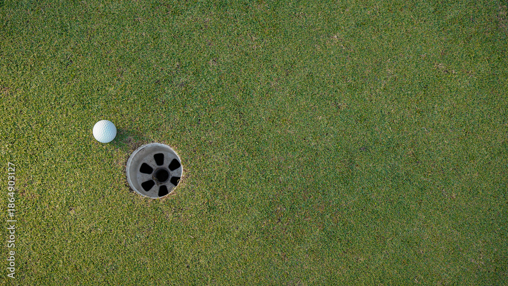 Obraz premium Golf ball is on a green lawn in a beautiful golf course with morning sunshine.