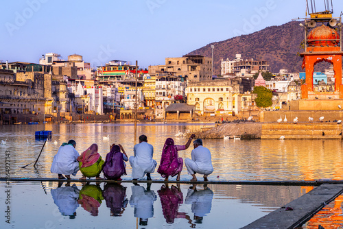 Pushkar Holy lake at sunset. Hindu pilgrims bathing in sacred Lake Pushkar (Sarovar) on ghats. Countless people in colourful attire gather to take a dip in the Holy Lake and pray to deities.