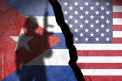 Flag of Cuba and USA painted on a concrete wall with soldier shadow