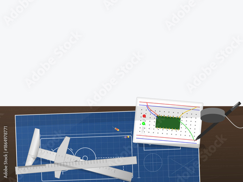 Blueprint and circuit board on a workbench with tools scattered around during an afternoon project in a workshop