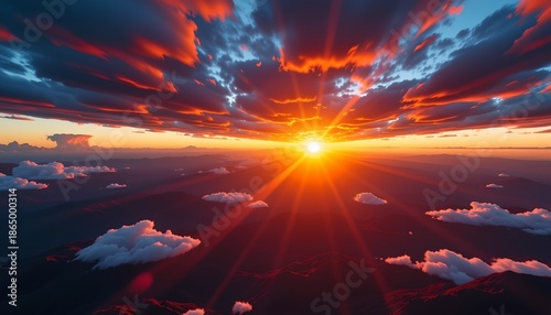 A breathtaking sunrise over a mountainous landscape, with a sky filled with radiant clouds that transition from dark to warm hues, culminating in a vibrant display of sunlight breaking through