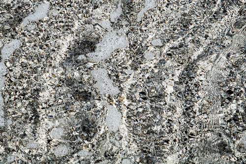 Canvas Print Foamy seawater over pebbly beach surface