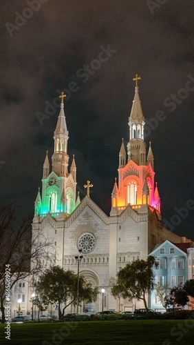 Wallpaper Mural A stunning white Gothic cathedral featuring twin spires beautifully illuminated with colorful lights at night. A perfect landmark for architecture and travel photography. Torontodigital.ca