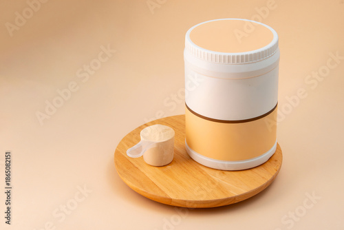Protein powder container and scoop on wooden tray.