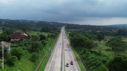 Aerial Drone View of Long Highway Through Green Rural Landscape Under Cloudy Sky