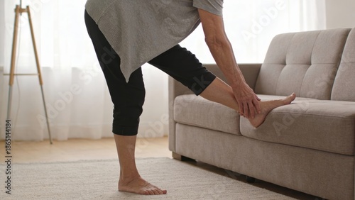 elderly Person stretching foot on sofa in a bright living room Retirement Living concept