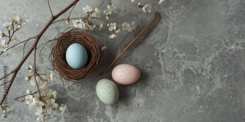 Pastel Easter Eggs in Twigs Nest with Floral Branches on Gray Marble Background Flat Lay