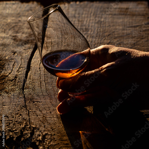hand holding whisky glass, rustic oak background