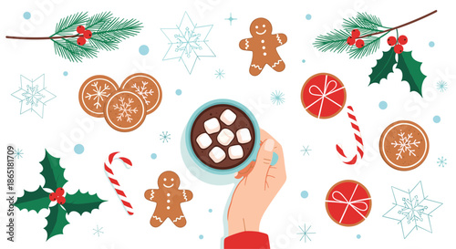 Top view of a hand holding a warm cup of hot chocolate with marshmallows surrounded by festive Christmas cookies and decor.