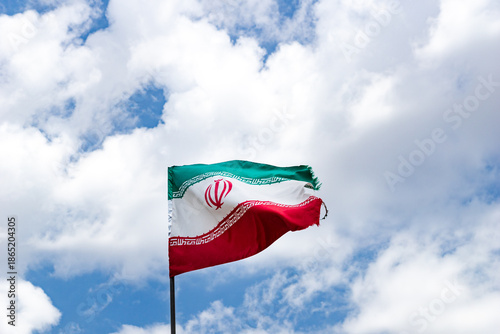 iranian flag waving against a clear blue sky on a flagpole. Flag of Iran Islamic Republic