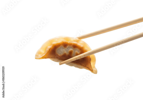 A single, golden-brown pan-fried dumpling, crispy bottom, tender top, delicately lifted by natural wooden chopsticks, against a transparent studio background, culinary excellence