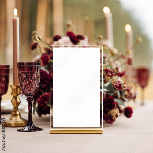 Elegant outdoor table setting with floral centerpiece, candles, and a blank acrylic table sign mockup