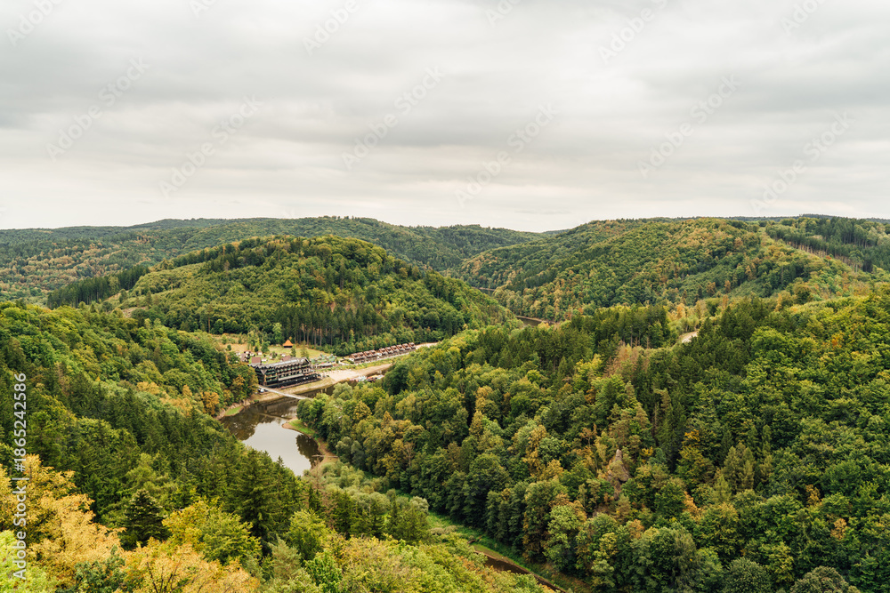 Fototapeta premium Village path through rural summer landscape panorama of the Góry Sowie (Owl Mountains), Poland, with green hills, meadows, forests, and clear blue sky in natural daylight.