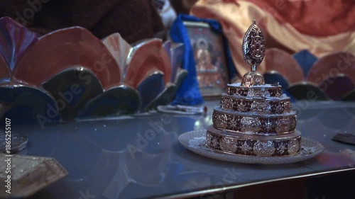 Intricate silver Buddhist stupa on altar, surrounded by ceremonial items and colorful fabrics, symbolizing peace and spirituality