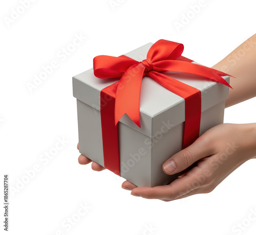 Pair of hands holding beautifully wrapped light gray square gift box decorated with bright red satin ribbon and bow ready for presentation