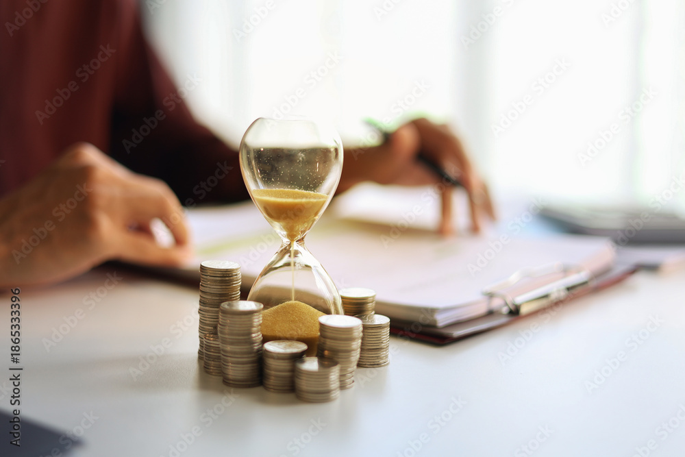 Foto Coin stacks and sand clock on the table