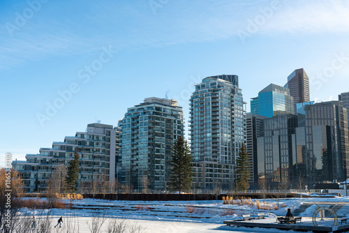 City skyline glistens under a clear sky, where modern buildings meet a wintry landscape, Calgary.