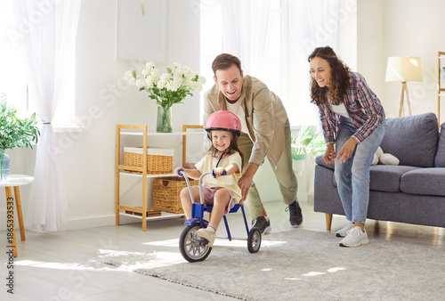 Φωτογραφία Happy family parents and daughter play at home riding bicycle