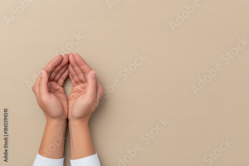 Hands holding gesture with cupped palms on beige background, symbolizing care, protection, or offering in minimal style close up editorial photo