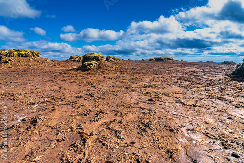 Eroded peatland landscape with exposed dark soil and isolated peat ‘islands’ under a bright blue sky