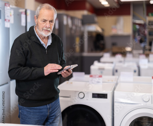 Bilde på lerret Eldery man buyer scanning qr code for electric dishwasher in home appliance stor