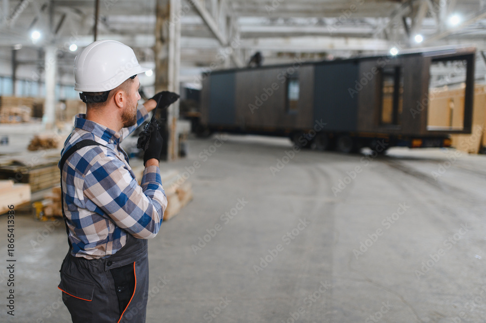 Obraz premium Foreman manages the loading of a prefabricated modular house to truck using walkie talkie