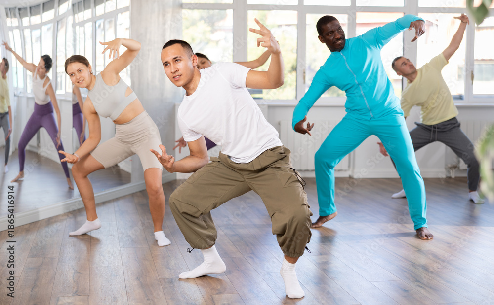Fototapeta premium During dance workshop, European guy with team of like-minded multinational people learn to perform elements of energy hip hop dance. Studio school for amateur and professional dancers