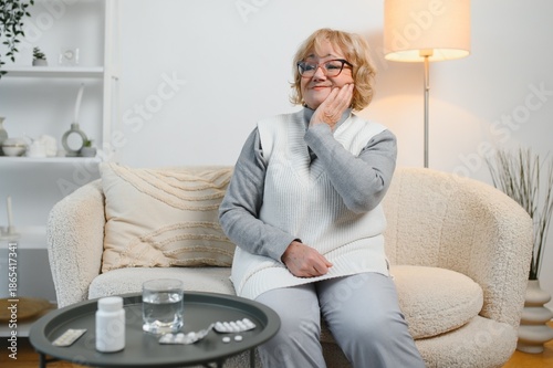Obraz na plátne Senior woman experiencing tooth pain, holding his cheek with pained expression,