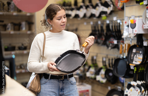Konstfotografi Girl customer inspect product range and selects frying pan
