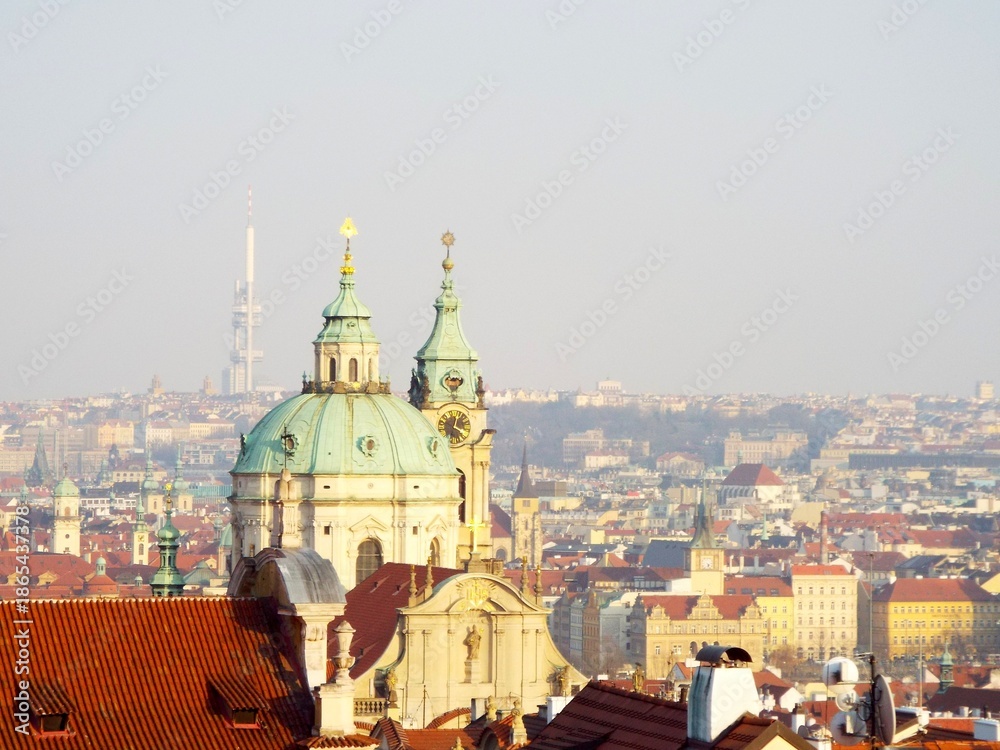 Obraz premium Prague Cityscape with Historic Church and Red Roofs at Sunset.