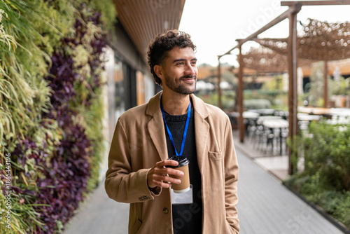 Foto Employee having coffee break outdoors at an eco-friendly office campus, walking