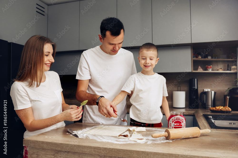 Obraz premium Family members work together in a kitchen preparing food on a table with rolling pin and ingredients during a daytime cooking activity