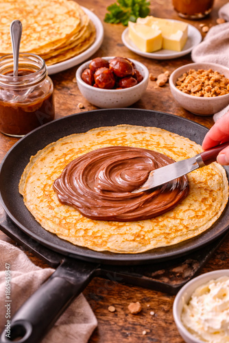 Crêpe maison en cours de préparation avec chocolat étalé à la spatule
