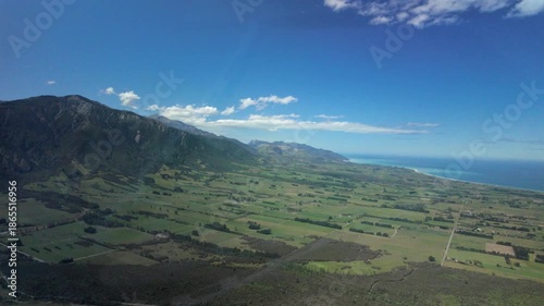 Helicopter cabin view over coastal farmland and mountains