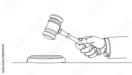 A hand holding a gavel in a courtroom setting with a judge's bench