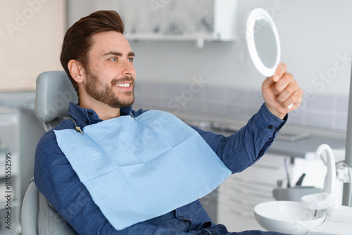 Valokuva Male patient looking at his beautiful healthy white smile, holding dental hand m