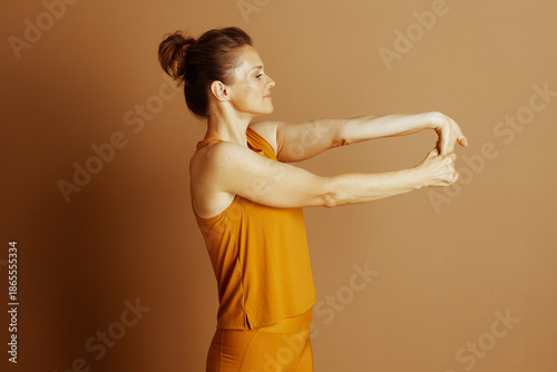 Fotografía A middle-aged woman in mustard yellow activewear performs a focused wrist and forearm stretch
