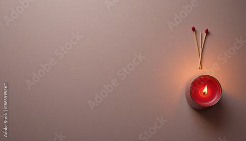 A lit minimal red candle with two matches on a plain beige background creating a romantic with mood