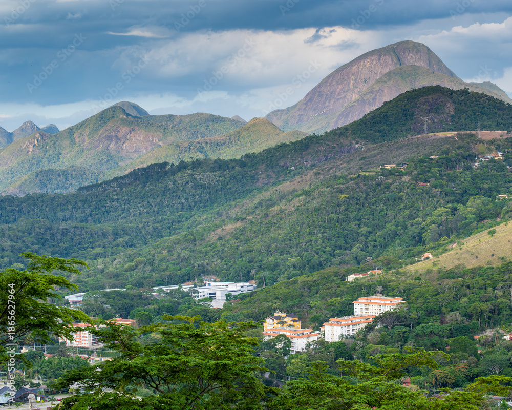 Fototapeta premium A mix of Atlatntic Forest, housing development and a mountain in the background in Petropolis, Rio de Janeiro, Itaipava, showing the use of the Atlantic Forest