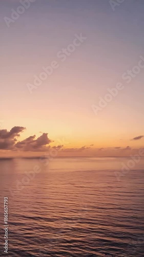 A tranquil ocean vista at either sunrise or sunset, showcasing soft pastel colors across the sky and calm, rippling water stretching towards the distant horizon.