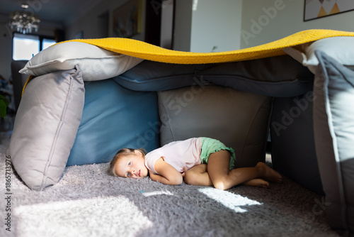 Принти на полотні Young girl lying inside a homemade cushion fort in a cozy living room