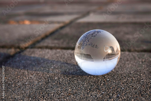 Fotografi glass, Crystal globe and earth ball, on a grid of square stones; a symbol of the greenhouse effect; earth globe