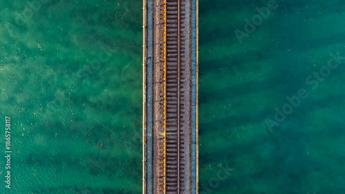 Foto Top-down aerial view of a railroad track bridge crossing clear turquoise ocean w