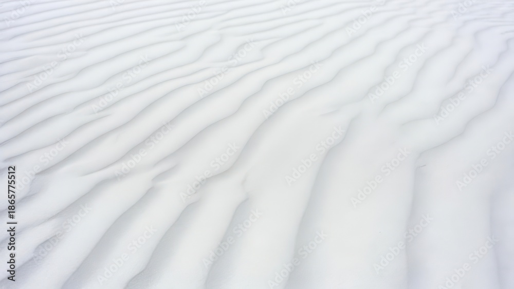 Obraz premium Aerial view of undulating white sand dunes with soft shadows and a minimalist aesthetic