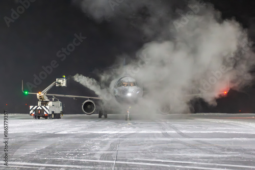 Ground deicing of a passenger jet plane on the night airport at winter