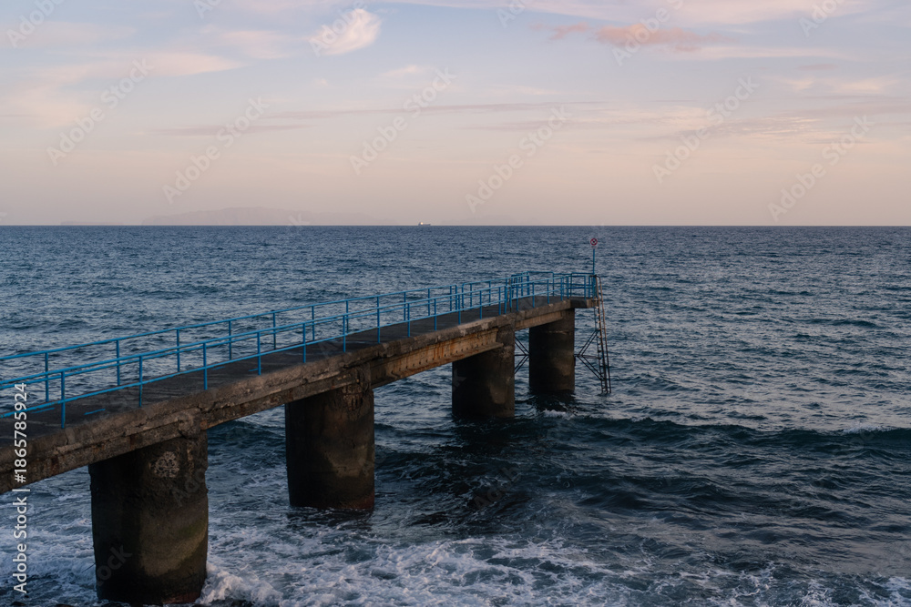 Obraz premium Concrete pier with blue railings over the ocean at sunset in Madeira