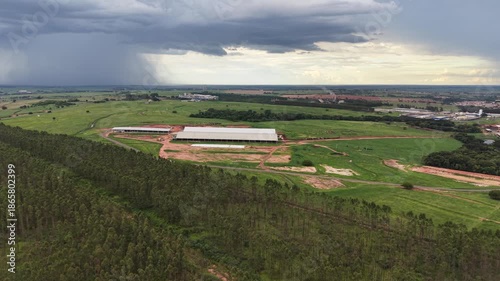 Aerial video footage of a large bovine confinement area under a stormy sky